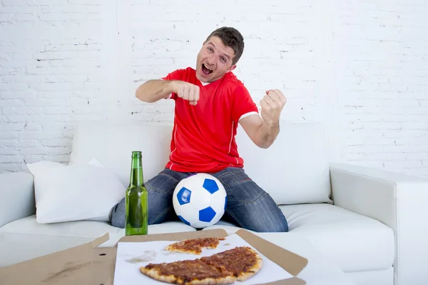 Молодой футбольный болельщик смотрит игру по телевизору в команде Джерси празднуя гол сумасшедший счастливы на диване — стоковое фото