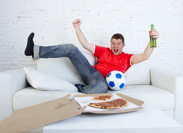 Junger Fußballfan sieht Spiel im Fernsehen im Trikot der Nationalmannschaft und feiert Tor verrückt glücklich auf Couch — Stockfoto