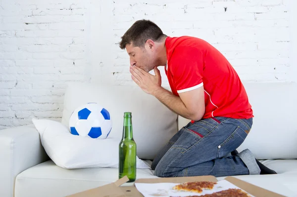 Joven hombre viendo partido de fútbol en la televisión nervioso y emocionado sufrimiento rezando dios por objetivo —  Fotos de Stock