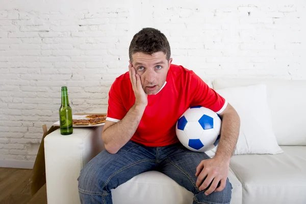 Jovem fã homem assistindo jogo de futebol na televisão vestindo camisa de equipe sofrendo nervoso e estresse — Fotografia de Stock