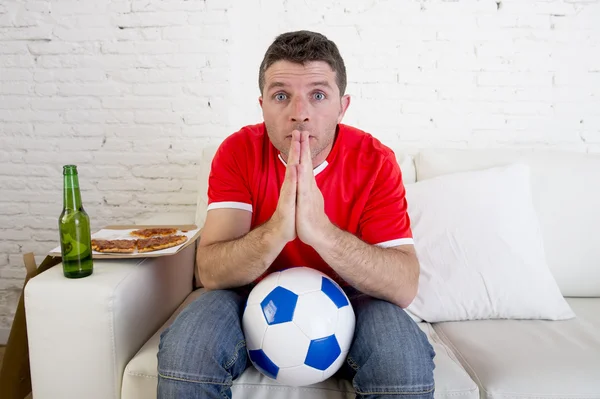 Young man watching football game on tv nervous and excited suffering stress praying god for goal — Φωτογραφία Αρχείου