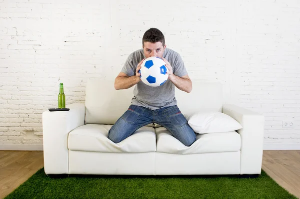 Tifoso di calcio guardando partita tv sul divano con tappeto passo erba i — Foto Stock