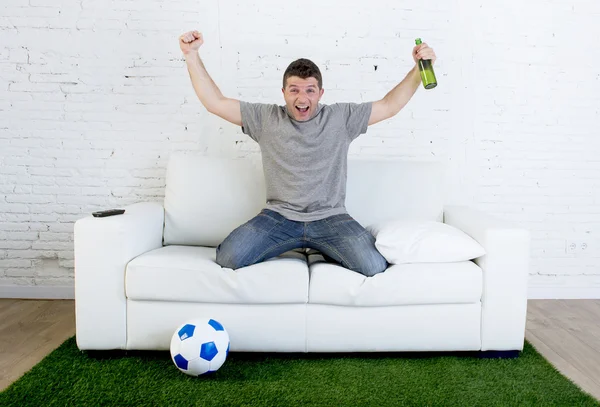 Fanático del fútbol viendo partido de televisión en sofá con alfombra de césped celebrando gol —  Fotos de Stock