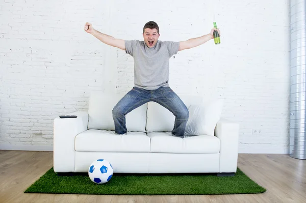 football fan watching tv match on sofa with grass pitch carpet celebrating goal