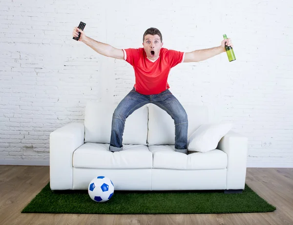 Fan de football regarder la télévision football célébrer le but dans le canapé sur l'herbe tapis émulant terrain de stade — Photo