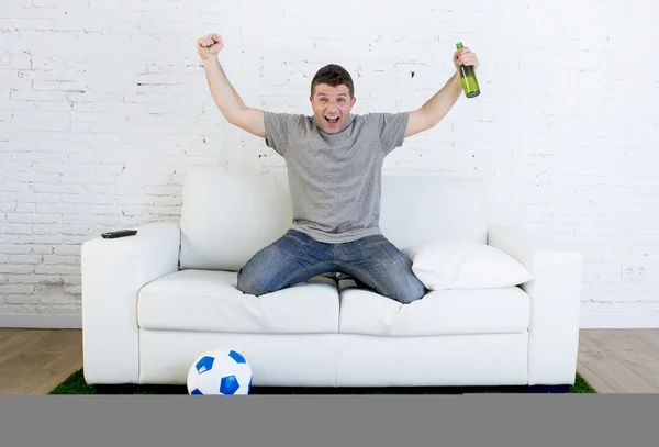 Fanático del fútbol viendo partido de televisión en sofá con alfombra de césped celebrando gol —  Fotos de Stock