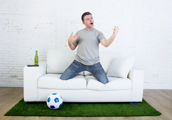 Fã de futebol assistindo jogo de tv no sofá com grama gramado tapete celebrando objetivo — Fotografia de Stock