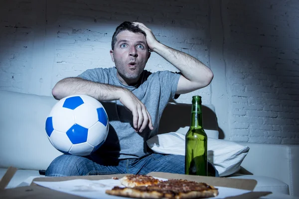 Młody człowiek oglądania meczu piłki nożnej w telewizji, nerwowy i podekscytowany, cierpienie stres na kanapie — Zdjęcie stockowe