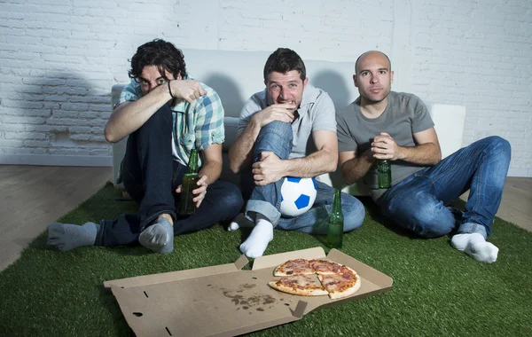 Друзья фанатичные футбольные болельщики смотрят телевизор матч с бутылками пива и пиццы страдают стрессом — стоковое фото