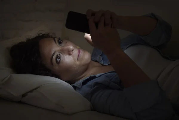 Wanita muda cantik berbaring di sofa rumah menggunakan ponsel konsep kecanduan internet — Stok Foto