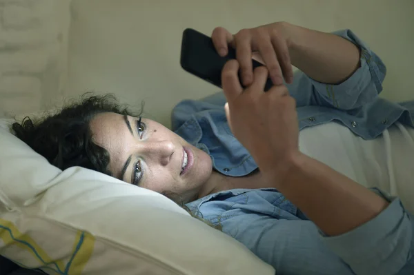 Feliz joven hermosa mujer en el sofá de casa utilizando mensajes de texto del teléfono móvil o disfrutar de la aplicación — Foto de Stock