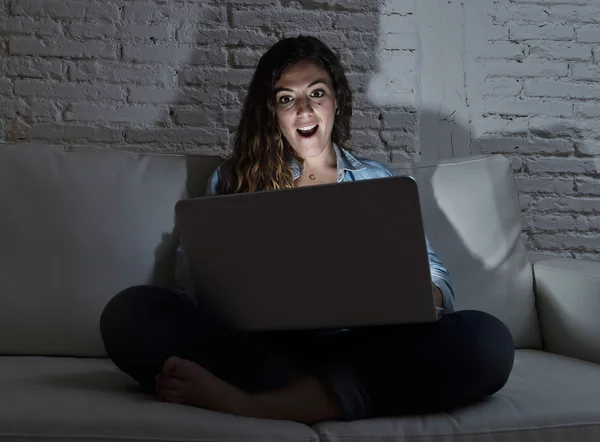 Séduisante femme détendue à la maison assise heureuse sur le canapé en utilisant un ordinateur portable dans la soirée sombre — Photo