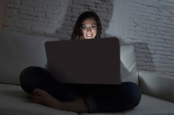 Menarik santai wanita di rumah duduk bahagia di sofa menggunakan laptop di malam hari — Stok Foto