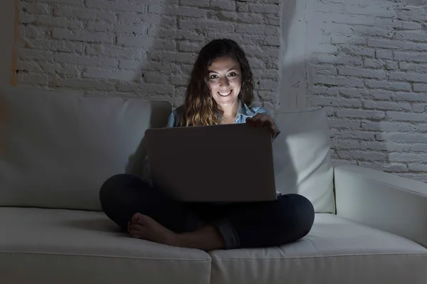 Menarik santai wanita di rumah duduk bahagia di sofa menggunakan laptop di malam hari — Stok Foto
