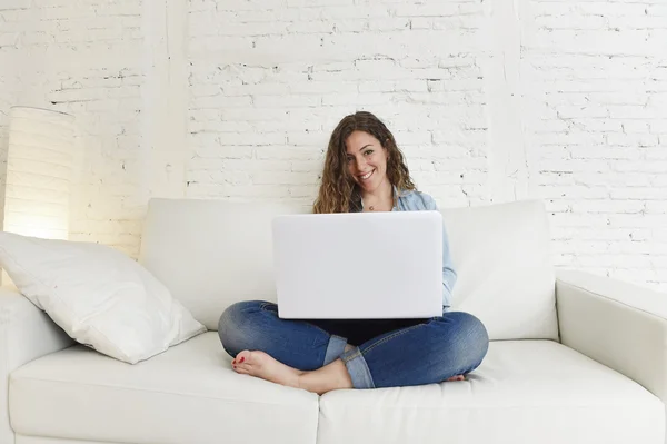 Tânără femeie spaniolă atractivă folosind laptop-ul stând relaxat lucrând pe canapeaua de acasă — Fotografie, imagine de stoc