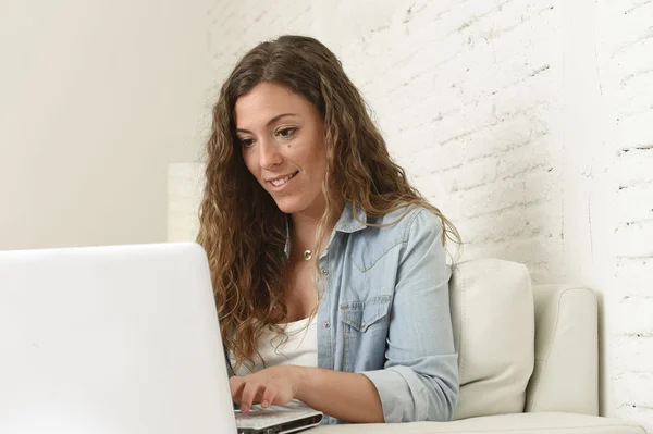 Молодая привлекательная испанская женщина с помощью ноутбука компьютер сидит расслабленной работы на домашнем диване — стоковое фото