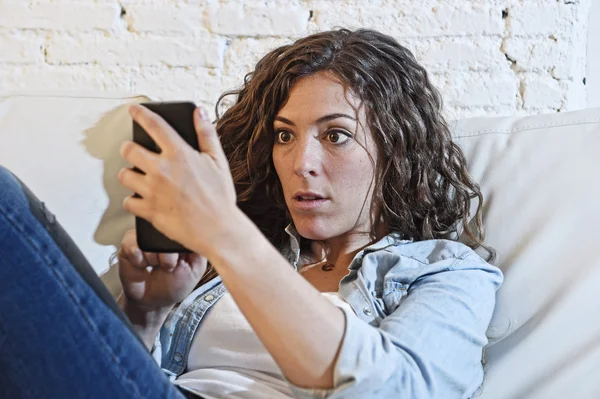 Іспаномовна жінка тримає мобільний телефон у божевільних очах соціальна мережа та концепція інтернет-залежності — стокове фото