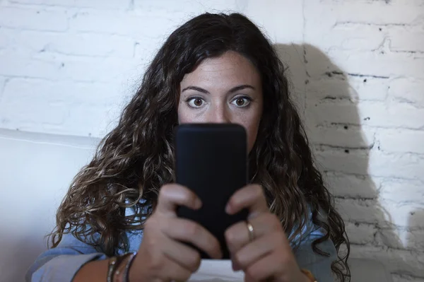 Hispânico mulher segurando telefone celular em olhos loucos rede social e internet vício conceito — Fotografia de Stock