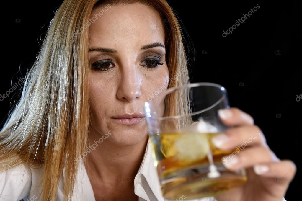 Drunk alcoholic woman alone in wasted depressed face holding and