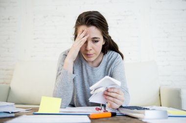 young worried woman suffering stress doing domestic accounting paperwork bills