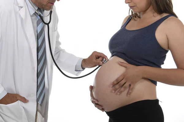 Hombre en medicina médico abrigo usando estetoscopio escuchando los latidos del corazón del feto en la mujer embarazada gran vientre — Foto de Stock