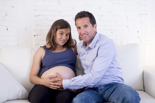 Junges verliebtes Paar auf der heimischen Wohnzimmercouch mit schwangerer Frau — Stockfoto