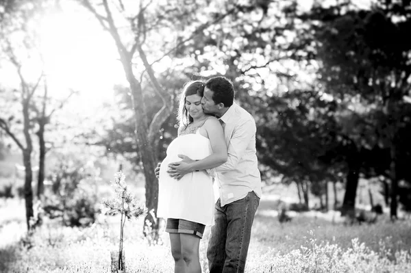 Młoda para szczęśliwy w miłości razem na zachód Słońca Krajobraz parku z kobieta w ciąży brzuch — Zdjęcie stockowe
