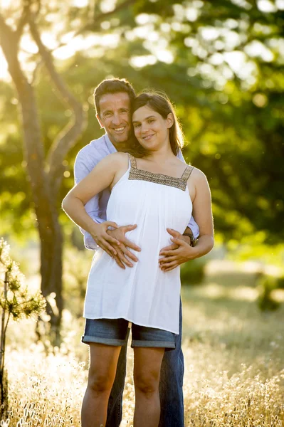 Young happy couple in love together on park landscape sunset with woman pregnant belly — Stock Photo, Image