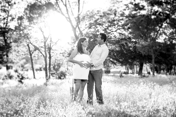 Joven feliz pareja en amor juntos en parque paisaje puesta de sol con mujer embarazada vientre —  Fotos de Stock