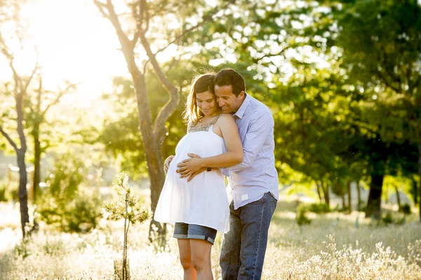 Young happy couple in love together on park landscape sunset with woman pregnant belly Stock Picture