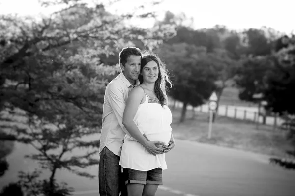 Happy couple in love together in park landscape on sunset with woman pregnant belly and man — Stock Photo, Image