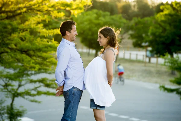 Feliz pareja en el amor juntos en el paisaje del parque en la puesta del sol con la mujer embarazada vientre y el hombre —  Fotos de Stock