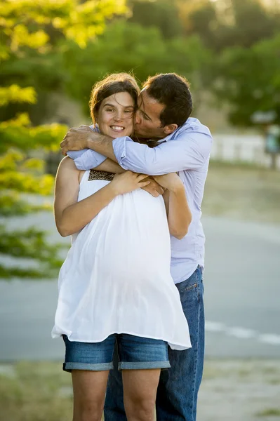 Glückliches verliebtes Paar in Parklandschaft bei Sonnenuntergang mit schwangerem Bauch und Mann — Stockfoto