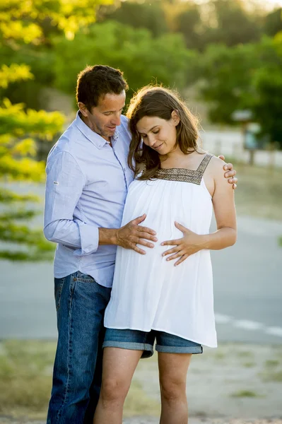 幸福的情侣，在公园景观上夕阳与女人怀孕的肚子和男人在一起的爱 — 图库照片