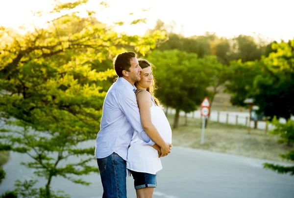 남자와 여 자가 임신 배 일몰에 공원 풍경에 함께 사랑에 행복 한 커플 — 스톡 사진