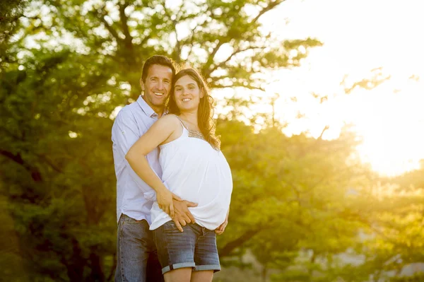 Happy couple in love together in park landscape on sunset with woman pregnant belly and man Stock Photo