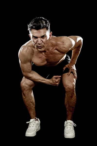Сильный здоровый человек с разорванным телом делает приседания упражнения, показывающие определенные плечи и бицепсы — стоковое фото