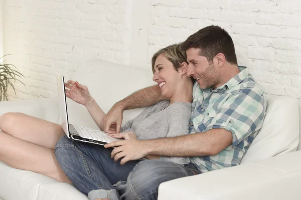 Красива пара закохана на дивані разом з ноутбуком — стокове фото