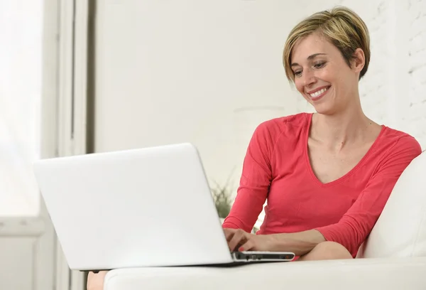 Young beautiful woman smiling happy working at home with laptop computer on sofa couch — Stock Photo, Image