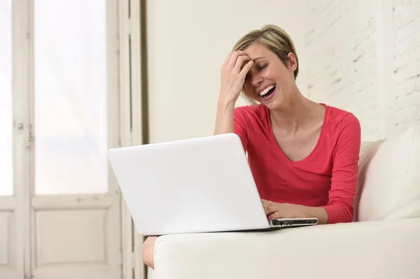 Jeune belle femme souriant heureux de travailler à la maison avec ordinateur portable sur canapé — Photo