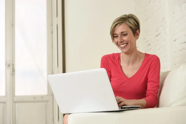 Jeune belle femme souriant heureux de travailler à la maison avec ordinateur portable sur canapé — Photo