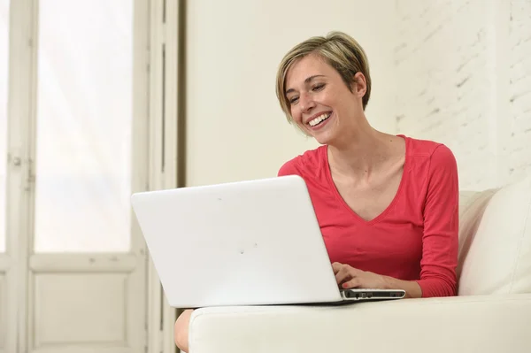 Junge schöne Frau lächelnd glücklich zu Hause mit Laptop-Computer auf Sofa-Couch arbeiten — Stockfoto