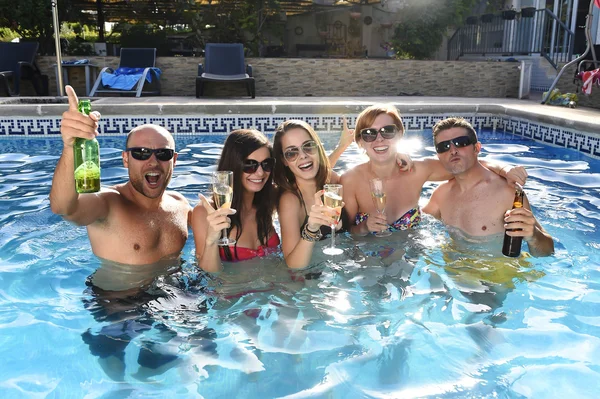 Hombres y mujeres atractivos felices en bikini teniendo baño en el complejo hotelero piscina beber cerveza — Foto de Stock