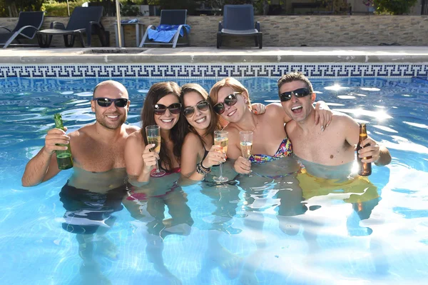 Счастливые привлекательные мужчины и женщины в бикини, купающиеся в бассейне отеля, пьющие пиво — стоковое фото
