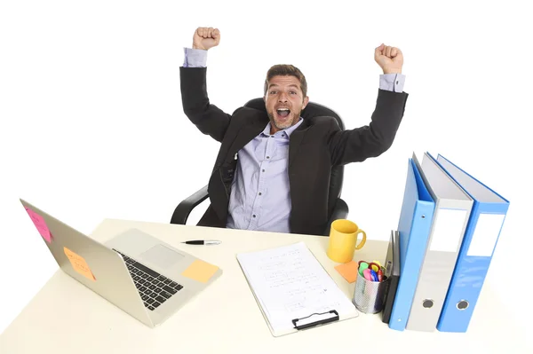 Jovem atraente empresário louco feliz fazendo sinal de vitória sentado na mesa do computador do escritório comemorando — Fotografia de Stock