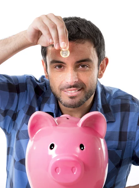 Jonge gelukkig man houden munt het ingebruikneming van roze piggy bank — Stockfoto