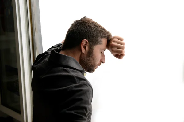 Hombre atractivo apoyado en la ventana sufriendo crisis emocionales y depresión —  Fotos de Stock