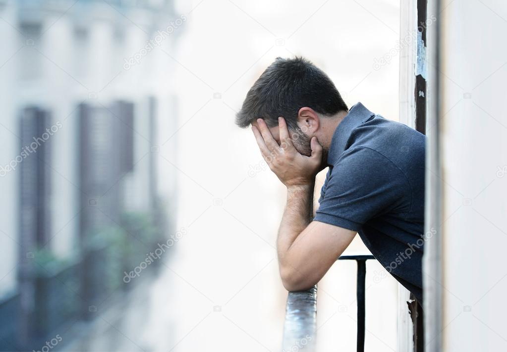 young man at balcony in depression suffering emotional crisis and grief