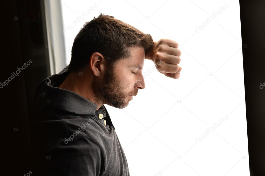 Attractive man leaning on window suffering emotional crisis and depression