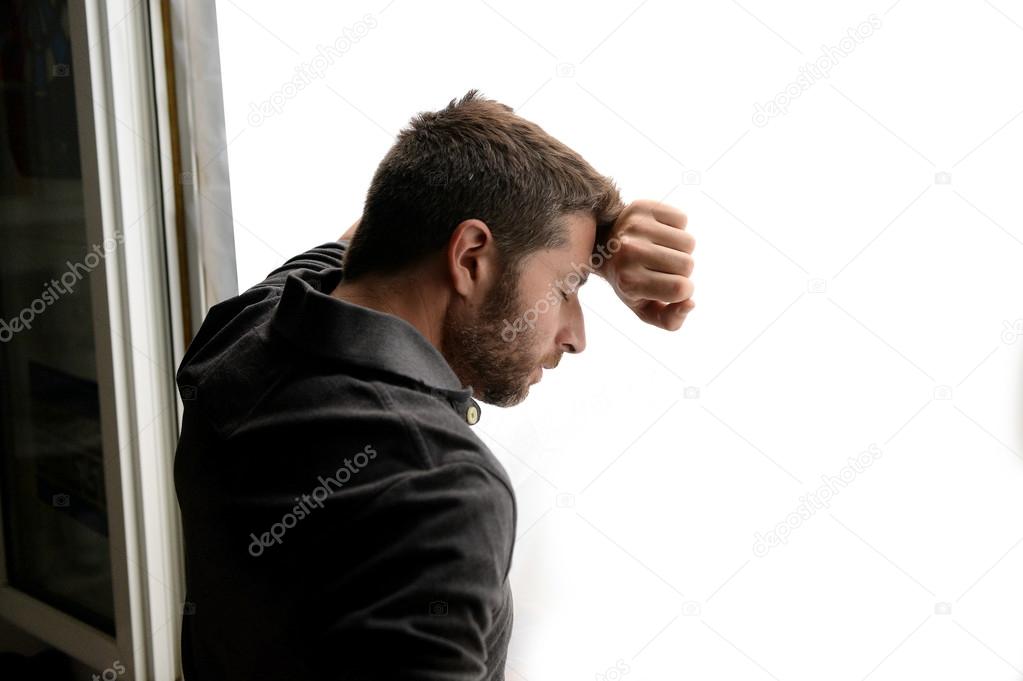 Attractive man leaning on window suffering emotional crisis and depression